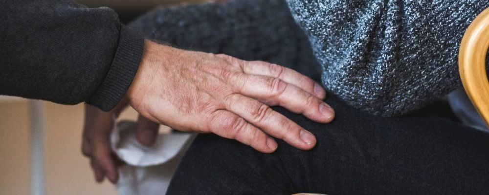 Närbild hand på knä.